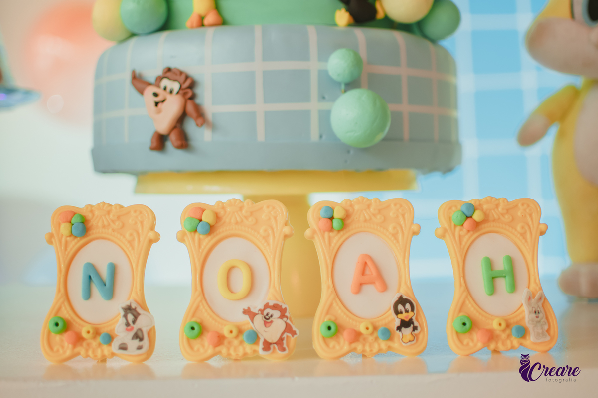 Plaquinhas de chocolate formando o nome Noah, personalizado com o tema Looney tunes para aniversário de 1 ano.