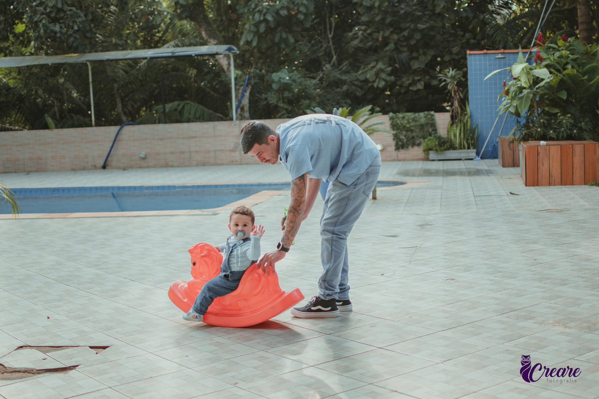 Um bebê brincando com seu pai, durante festa de aniversário de 1 ano.