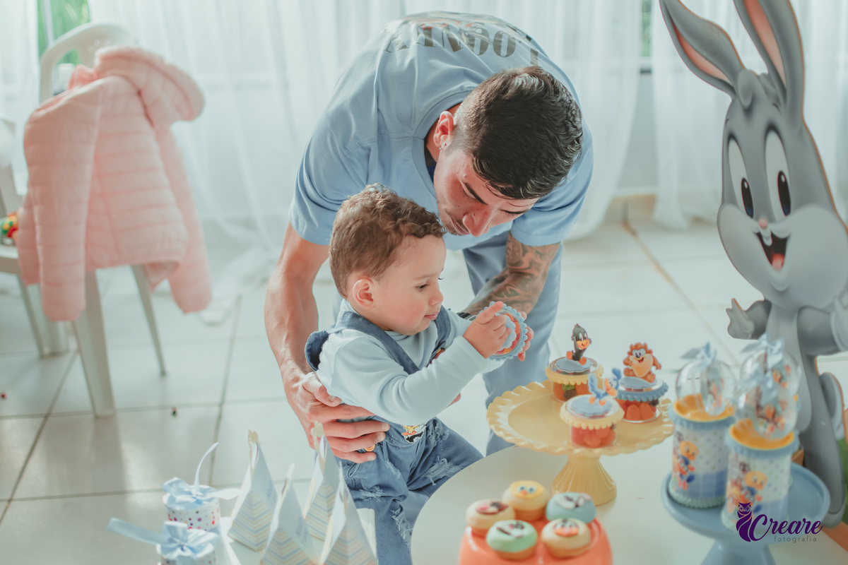 Um bebê brincando com seu pai, durante festa de aniversário de 1 ano.
