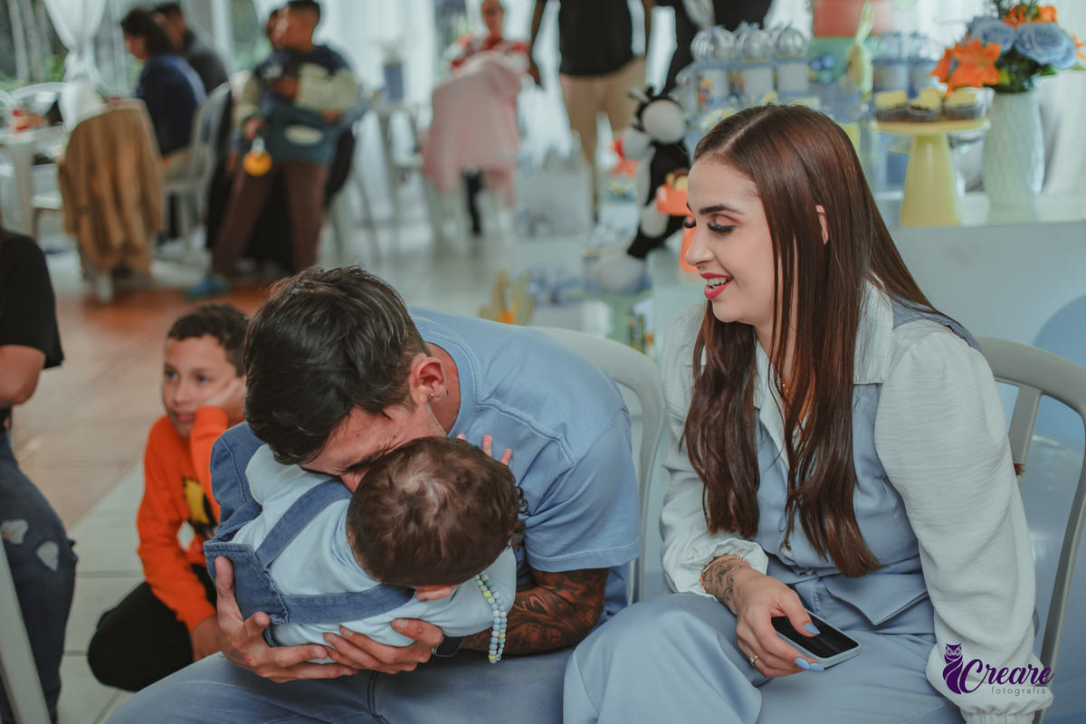 Um bebê brincando com seu pai, durante festa de aniversário de 1 ano.