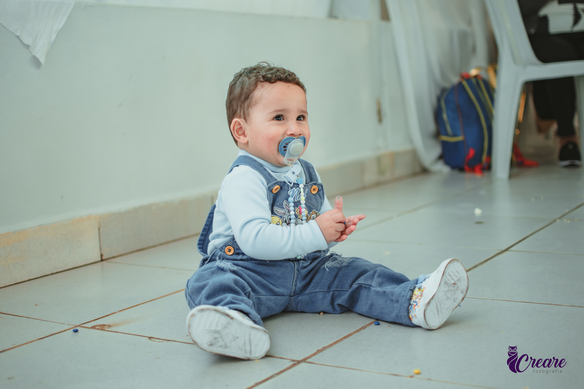 Um bebê brincando no chão durante sua festa de aniversário de 1 ano.