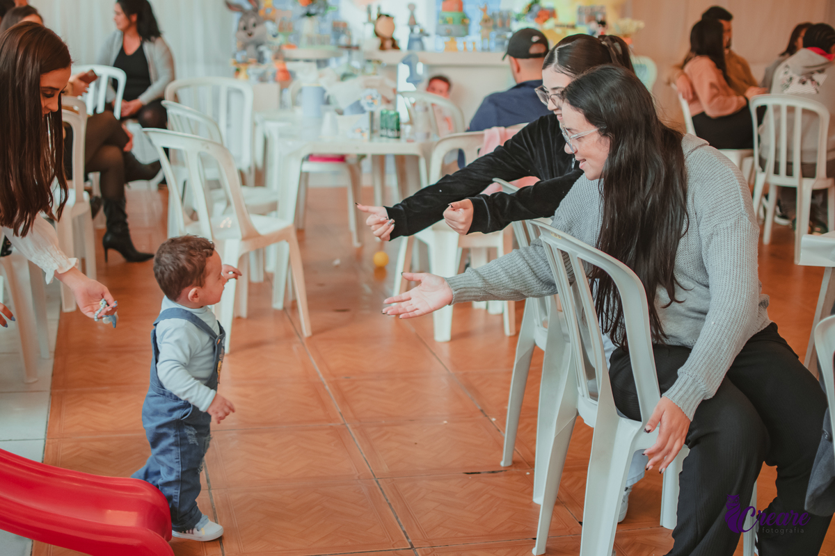 Um bebê brincando com convidados da sua festa de aniversário de 1 ano.
