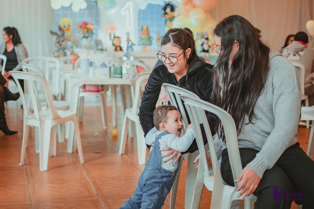 Um bebê brincando com convidados da sua festa de aniversário de 1 ano.