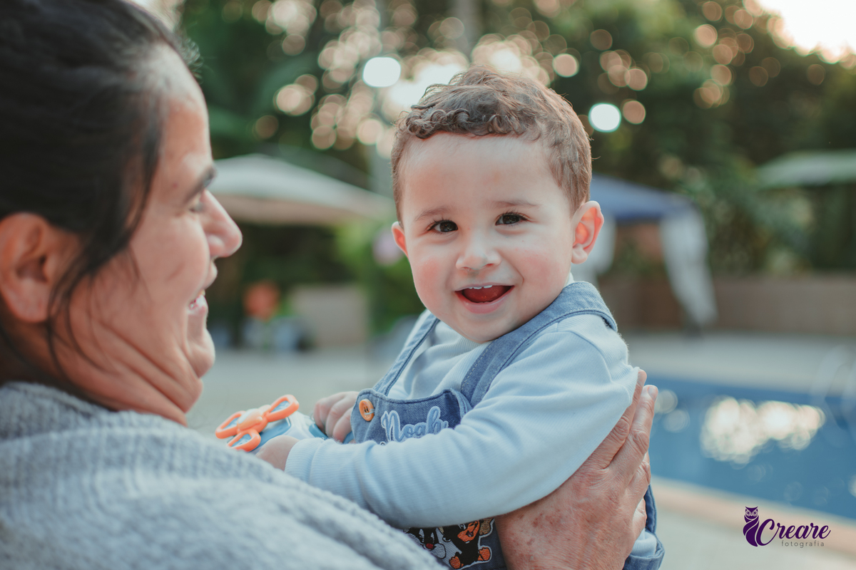 Um bebê brincando com convidados e sorrindo durante a sua festa .de aniversário de 1 ano