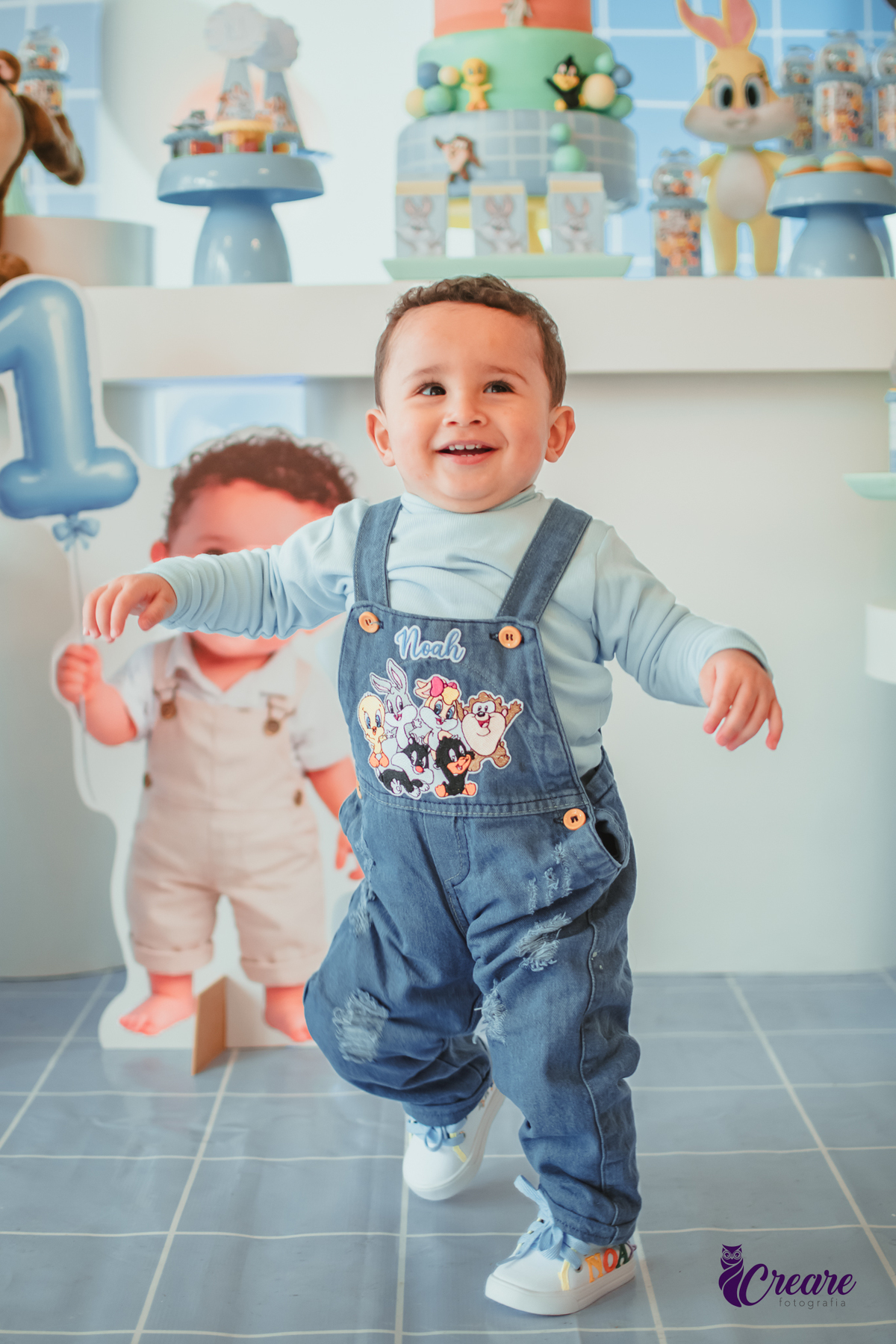 Um bebê em frente a sua mesa de decoração, durante o aniversário de  1 ano.