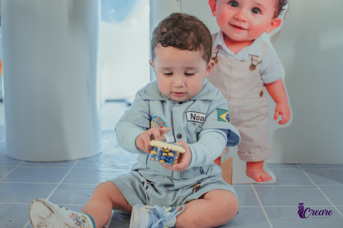 Um bebê, vestido com roupas personalizadas do desenho Baby Looney tunes e brincando em sua festa de aniversário de 1 ano.