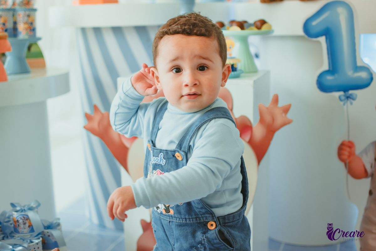 Um bebê em frente a sua mesa de decoração, durante o aniversário de  1 ano.