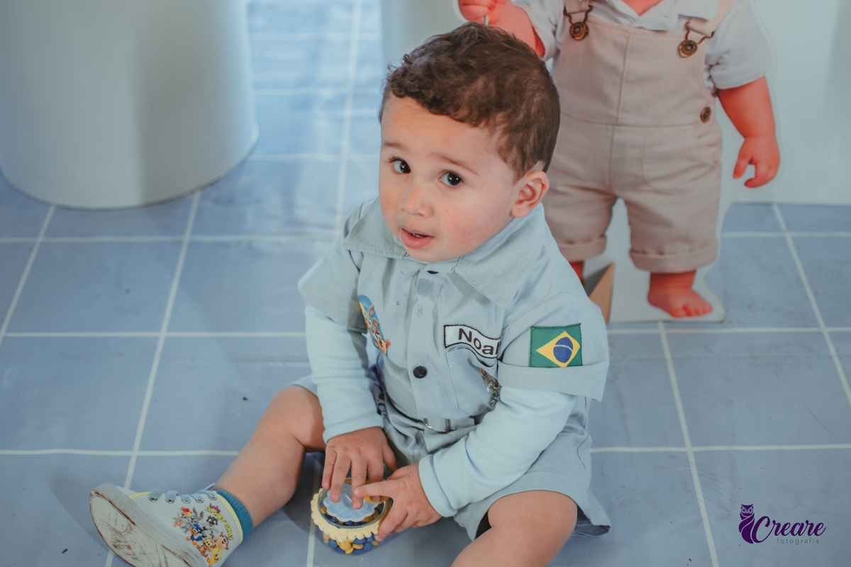 Um bebê, vestido com roupas personalizadas do desenho Baby Looney tunes e brincando em sua festa de aniversário de 1 ano.
