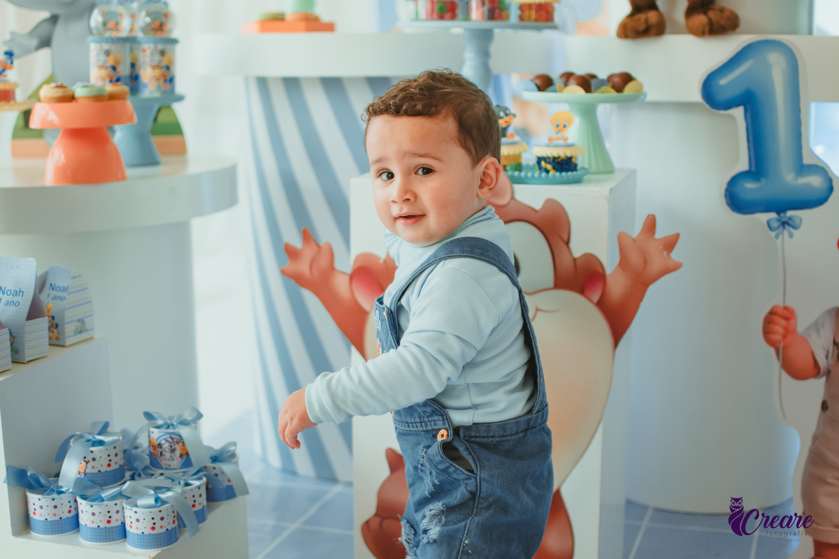 Um bebê em frente a sua mesa de decoração, durante o aniversário de  1 ano.