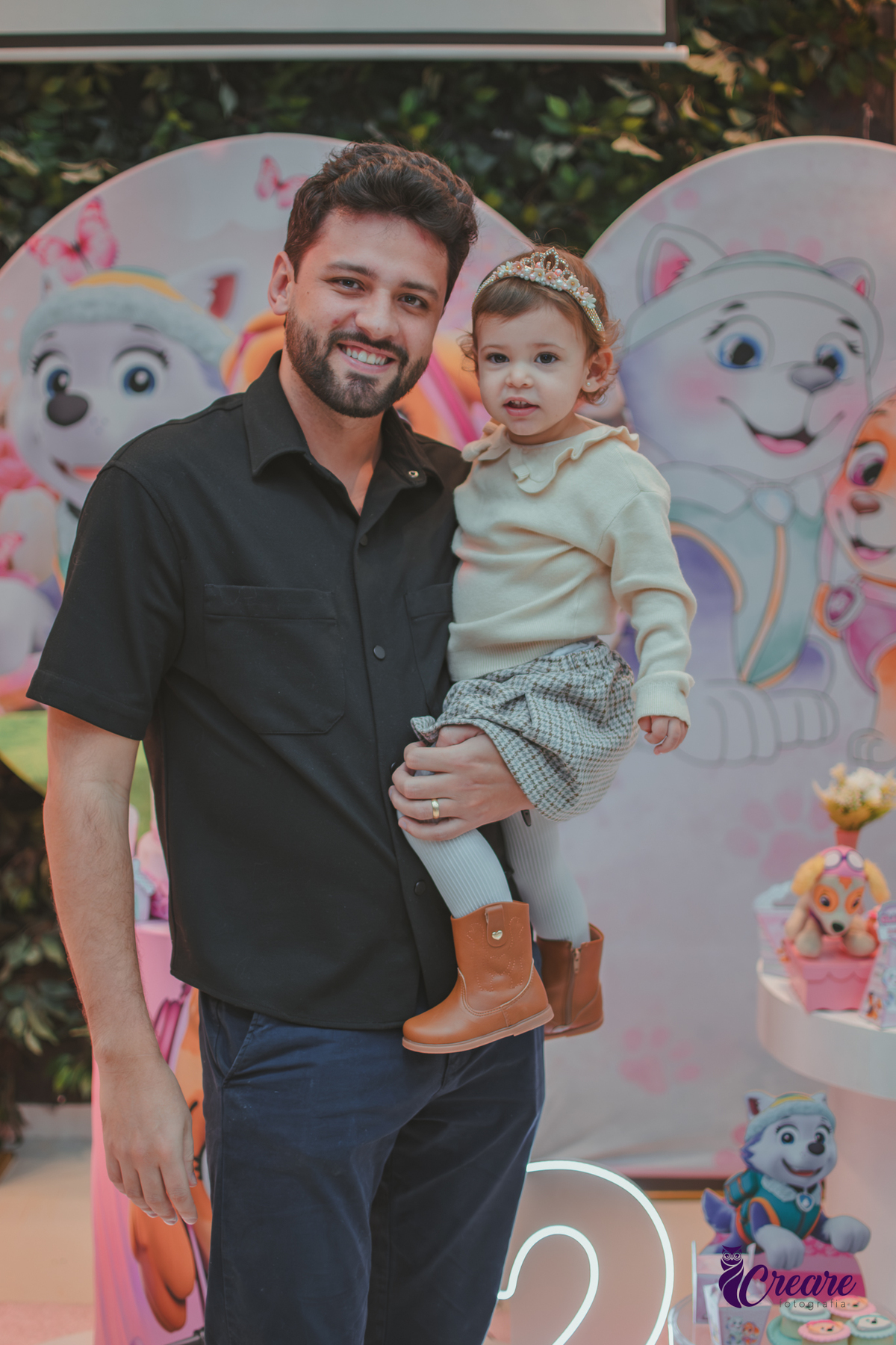 um homem com sua ffilha de dois anos em frente a mesa de decoração do aniversário da criança no Buffet Happy House em Santo André.