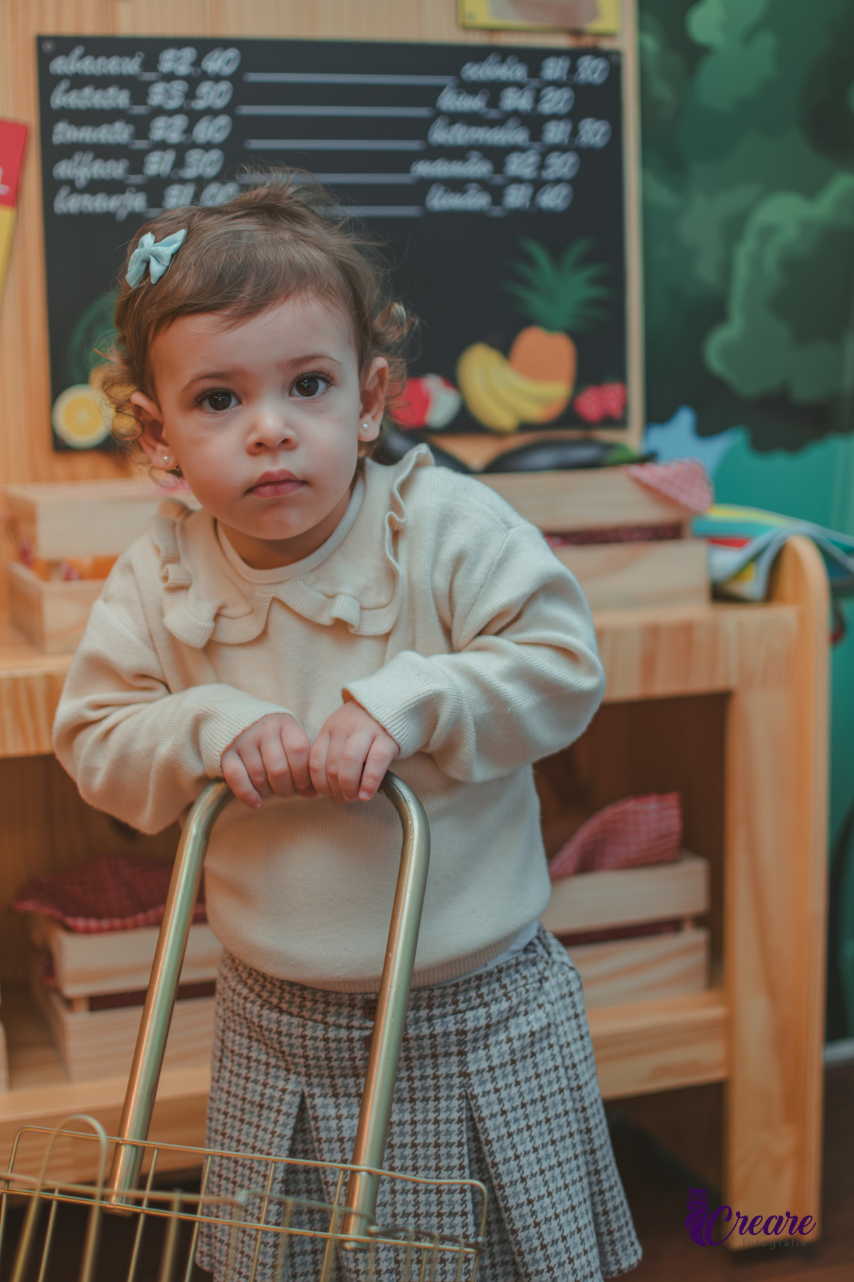 Uma menina empurrando carinho de feira de brinquedo, durante sua festa de aniversário de 2 anos no Buffet Happy House.
