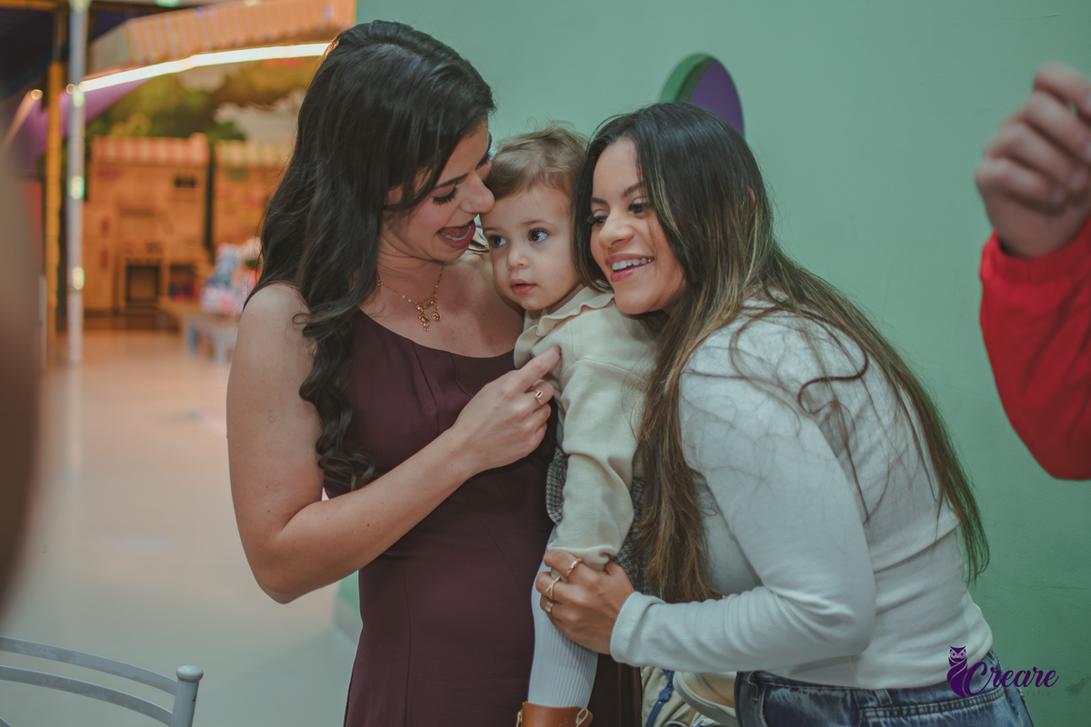 Duas mulheres abrançando uma criança de dois ano durante a festa de aniversário no Buffet Happy House em Santo André.