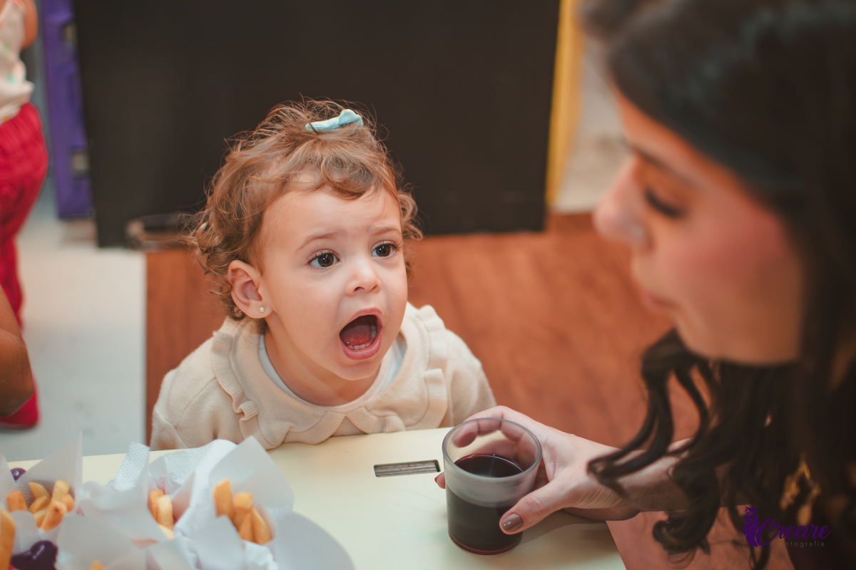 Uma criança sentada em uma mesa, na hora do lanchinho durante seu aniversário de 2 anos no buffet Happy House.
