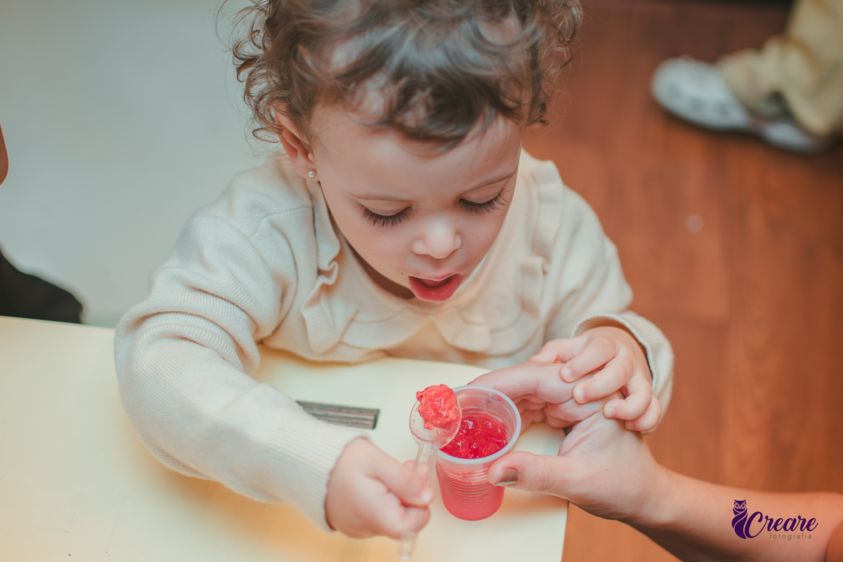 Uma criança comendo gelatinha, na hora do lanchinho durante seu aniversário de 2 anos no buffet Happy House.