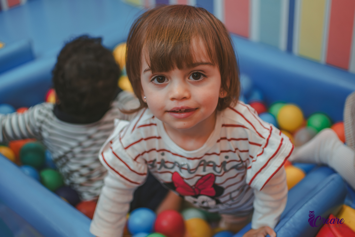 Uma criança na piscina de bolinhas durante um aniversário infantil.