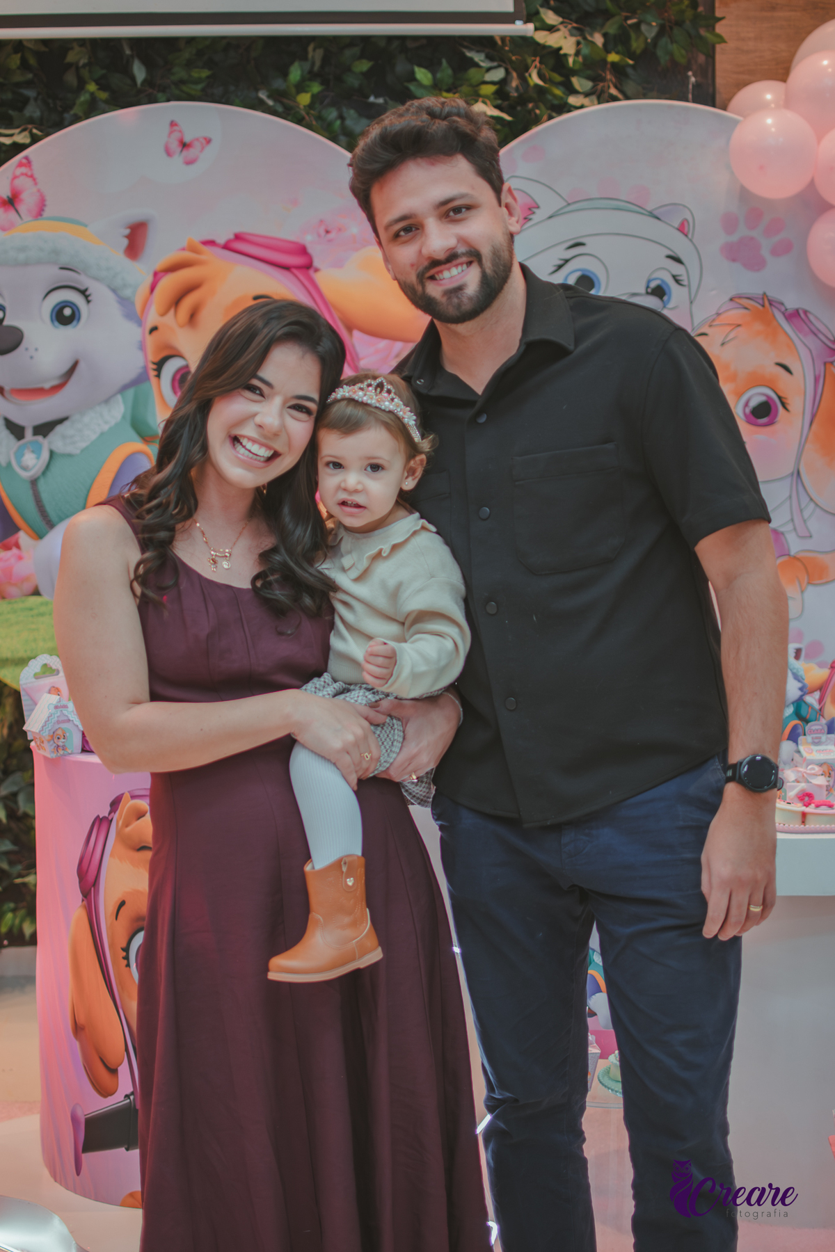 Uma família com uma menina de dois anos em frente a mesa de decoração do seu aniversário no Buffet Happy House em Santo André.