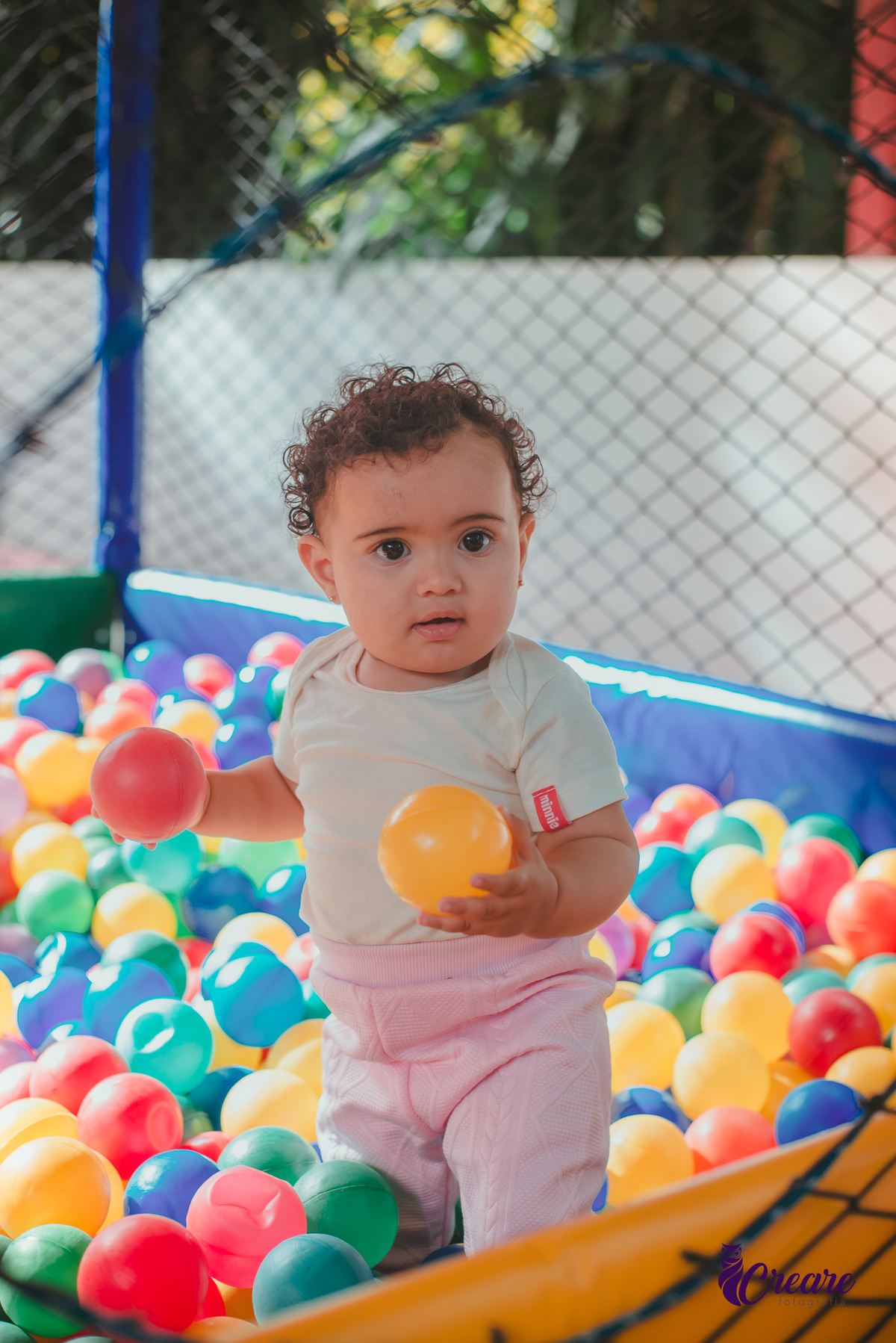 Uma bebê brincando na piscina de bolinhas durante seu aniversário de 1 ano.
