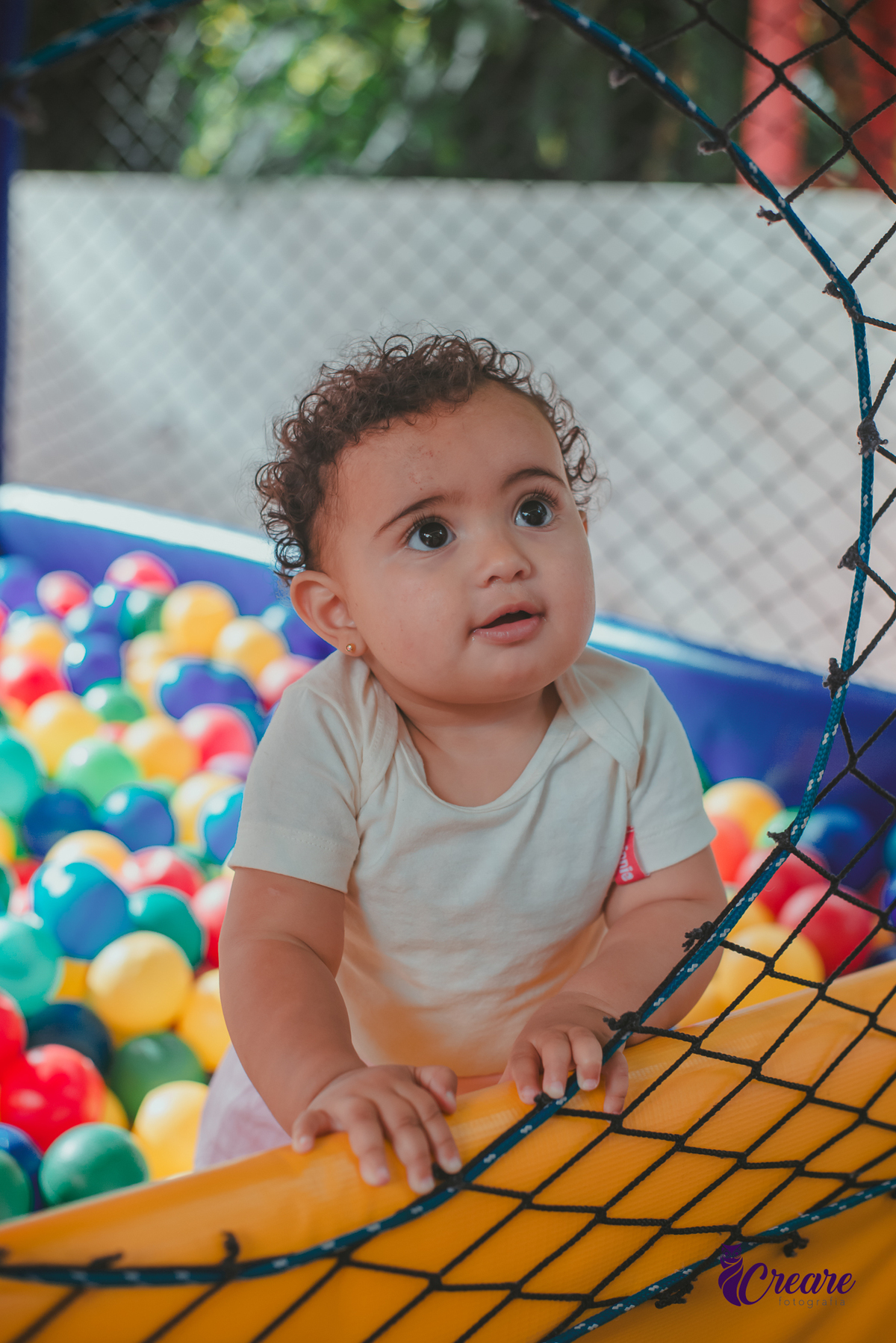 Uma bebê brincando na piscina de bolinhas durante seu aniversário de 1 ano.