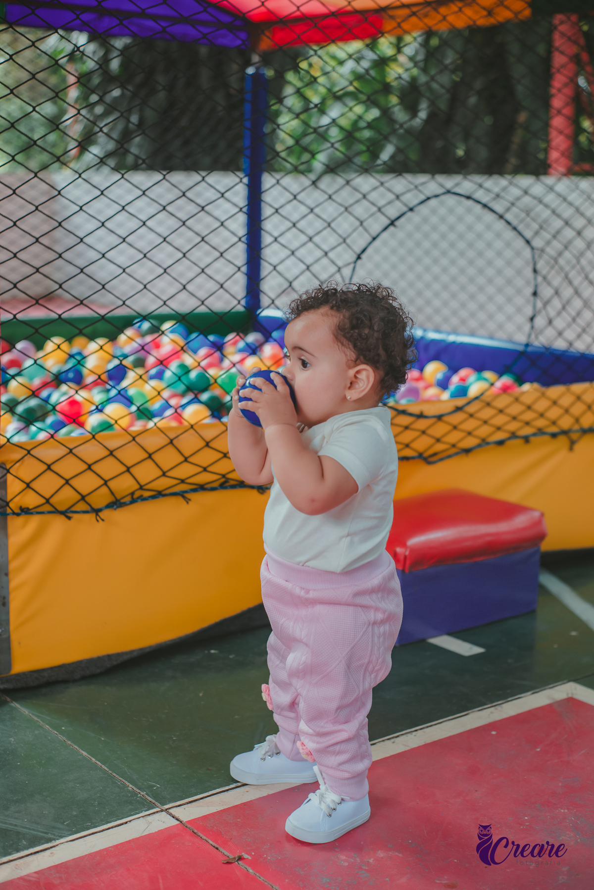 Uma bebê brincando na piscina de bolinhas durante seu aniversário de 1 ano.