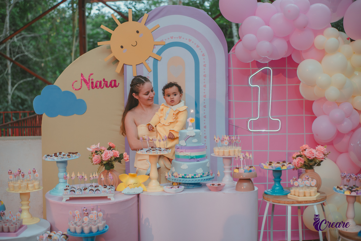 Uma mulher e uma bebê cantando parabéns, durante a festa de aniversário de 1 ano.