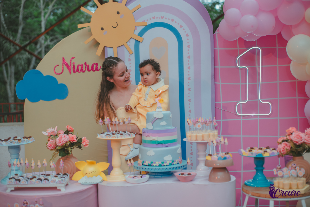 Uma mulher e uma bebê cantando parabéns, durante a festa de aniversário de 1 ano.