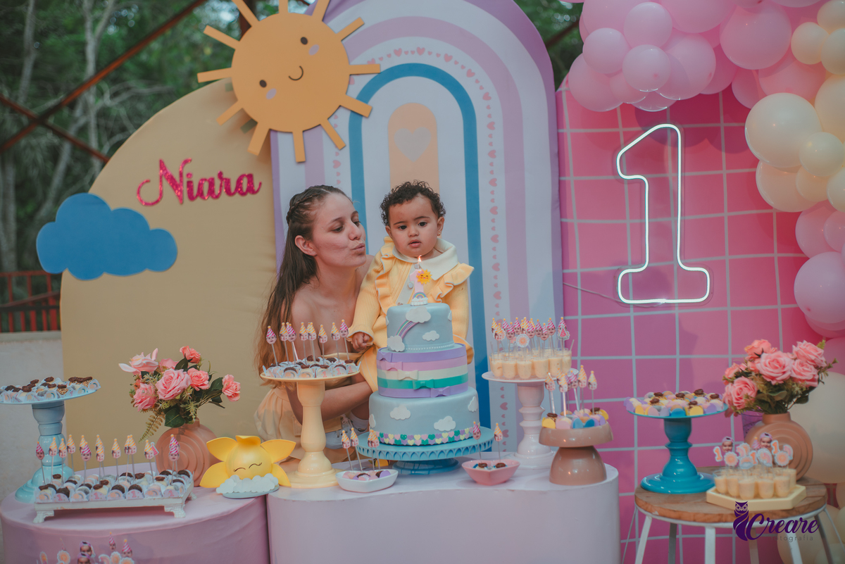 Uma mulher e uma bebê soprando velinha na parabéns, durante a festa de aniversário de 1 ano.