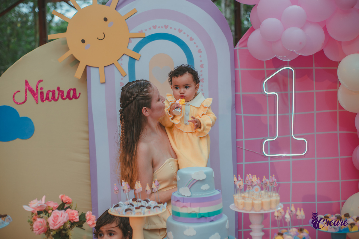 Uma mulher e uma bebê soprando velinha na parabéns, durante a festa de aniversário de 1 ano.