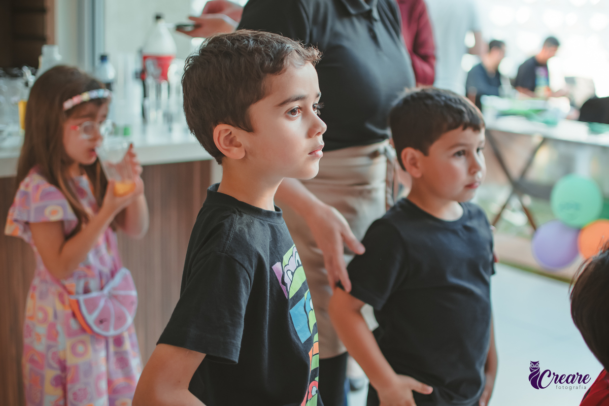 Um menino com seu amiguinhos ouvindo atentamento as orientações da brincadeira, durante sua festa de aniversário em casa.