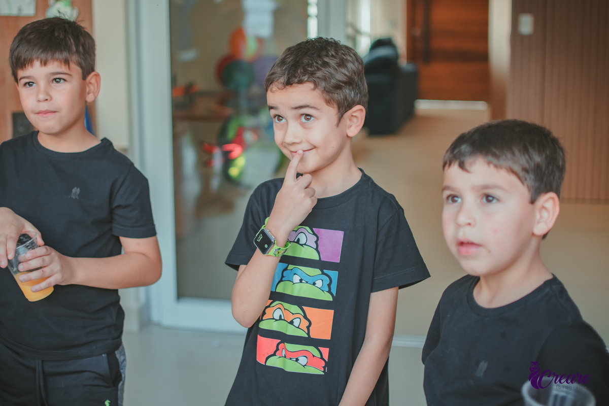 Um menino com seu amiguinhos ouvindo atentamento as orientações da brincadeira, durante sua festa de aniversário em casa.