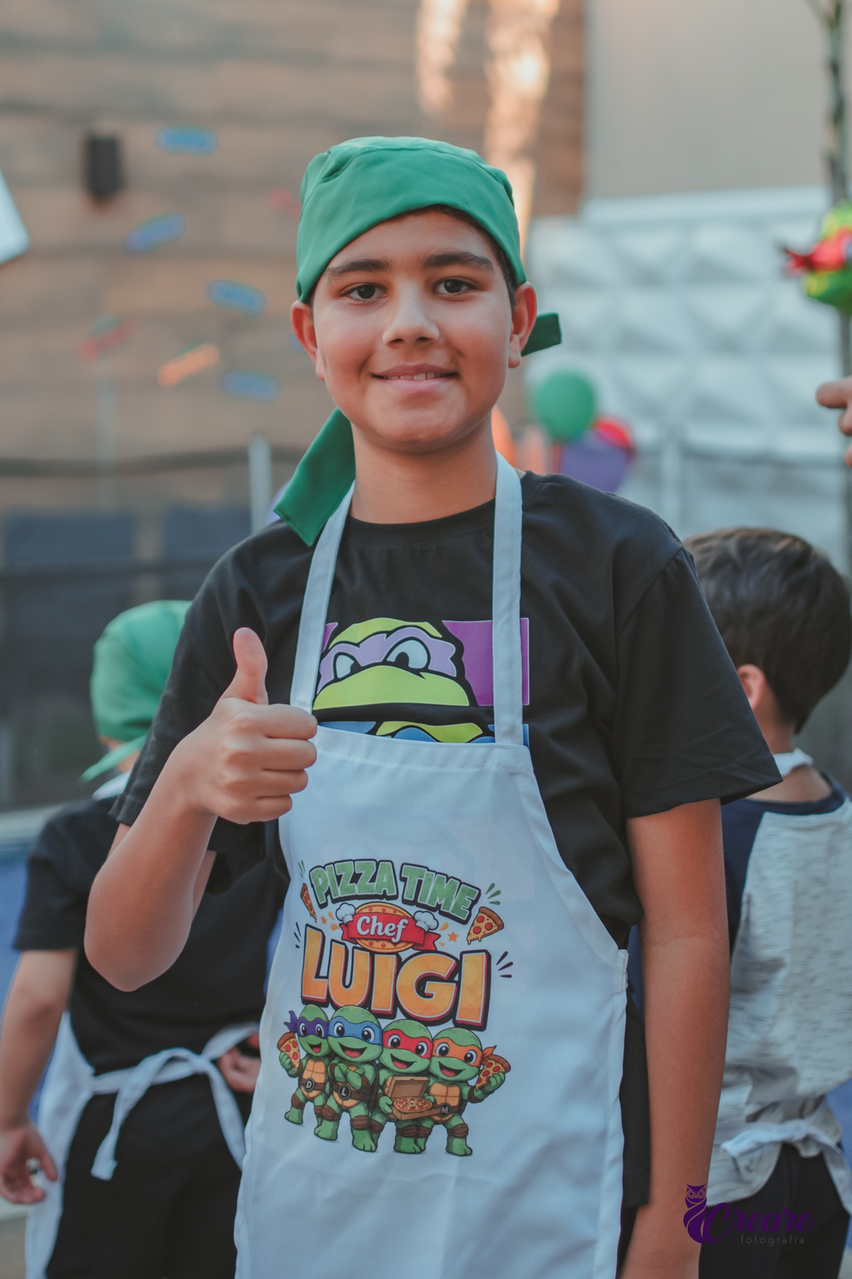 Um menino com avental personalizado, para uma oficina de pizza, durante festa de aniversário em casa.