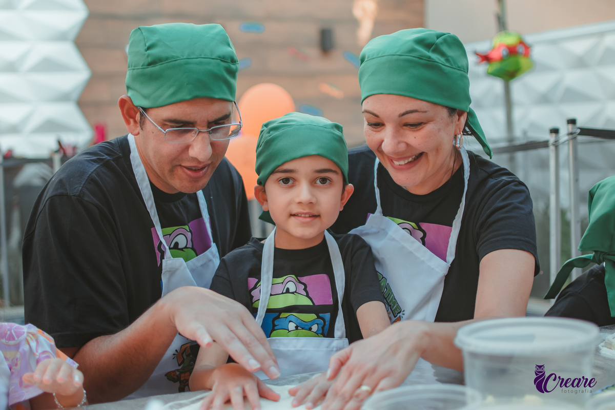 Uma familia preparando pizza, durante festa de aniversário infantil em casa.