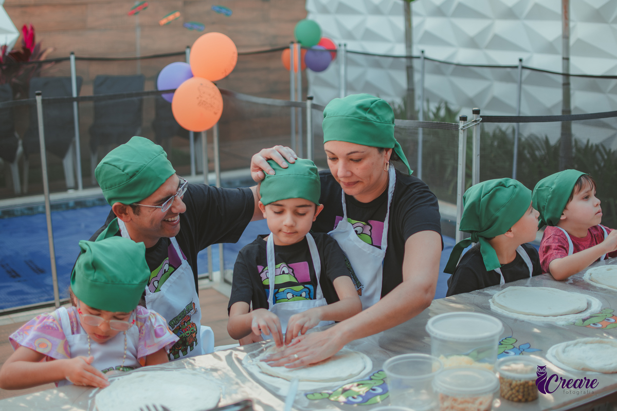 Uma familia preparando pizza, durante festa de aniversário infantil em casa.