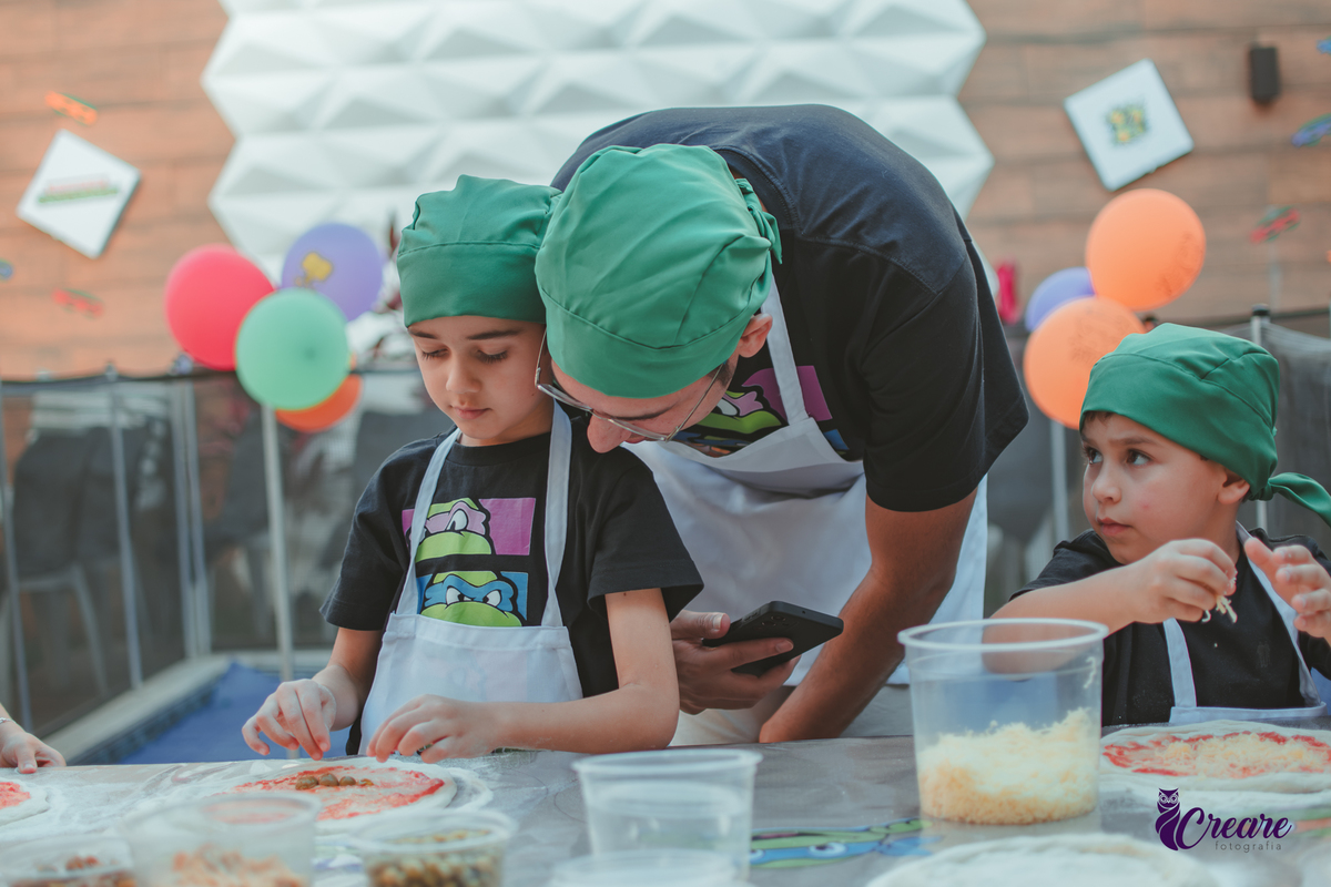 Um menino e seu pai, preparando pizza durante aniversário infantil em casa.