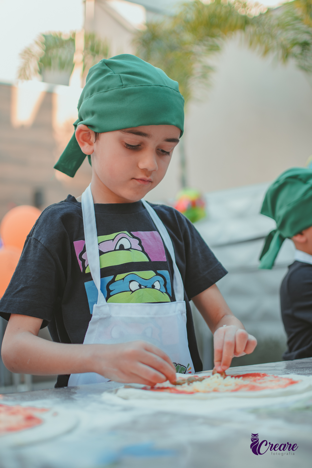 Crianças preparando pizza durante brincadeira de festa de aniversário infantil em casa.