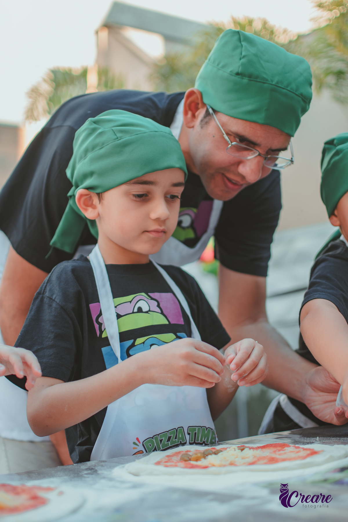 Um menino e seu pai, preparando pizza durante aniversário infantil em casa.