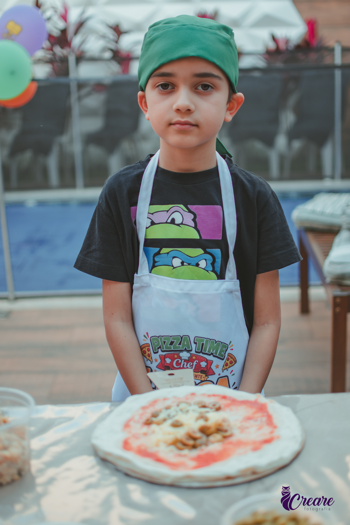 Um menino mostrando sua pizza, feita durante oficina de pizza em seu aniversário em casa.
