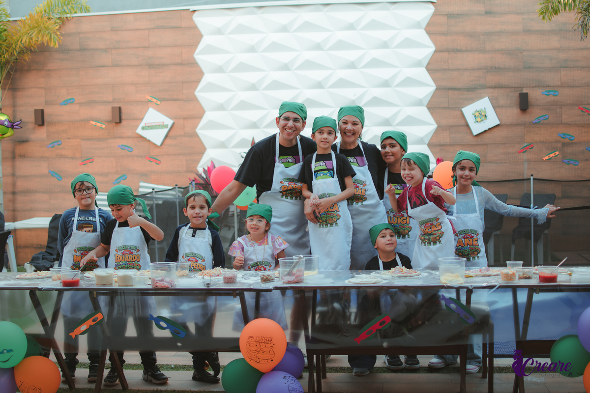 Crianças preparando pizza durante brincadeira de festa de aniversário infantil em casa.