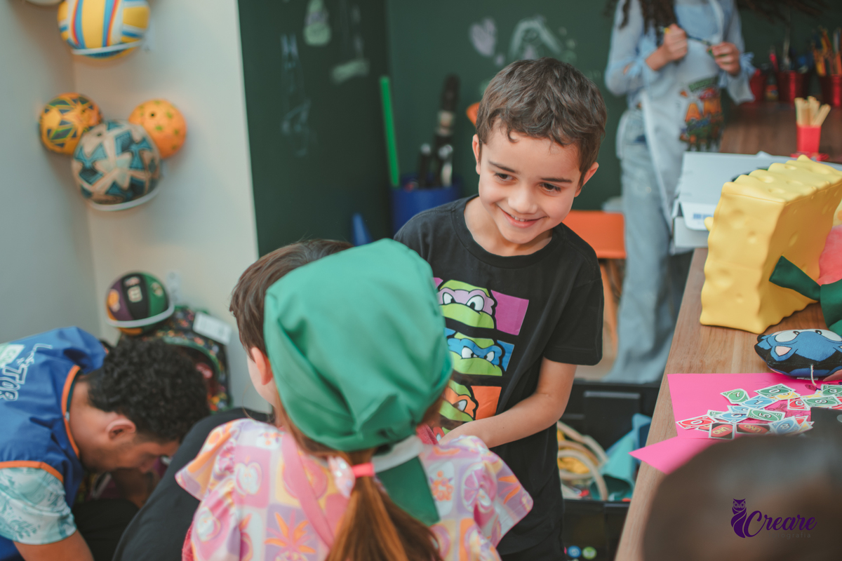 Crianças brincando de um levantar o outro, durante festa de aniversário em casa.