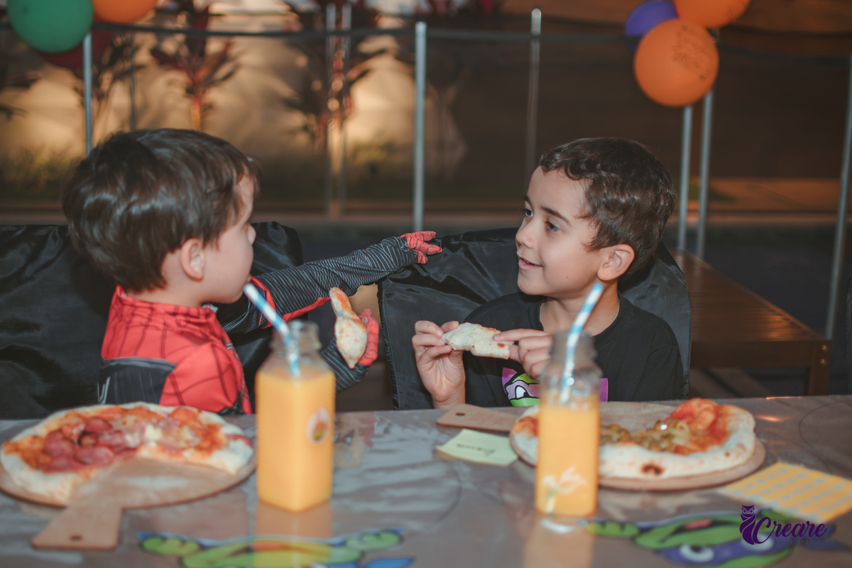 várias criança comendo a pizza que produziram na oficina de pizza, durante sua festa de aniversário em casa.