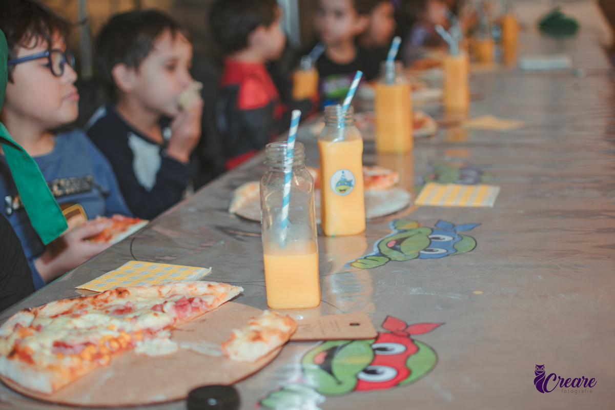 Detalhes de uma mesa com suco e pizza, na hora do lanchinho.