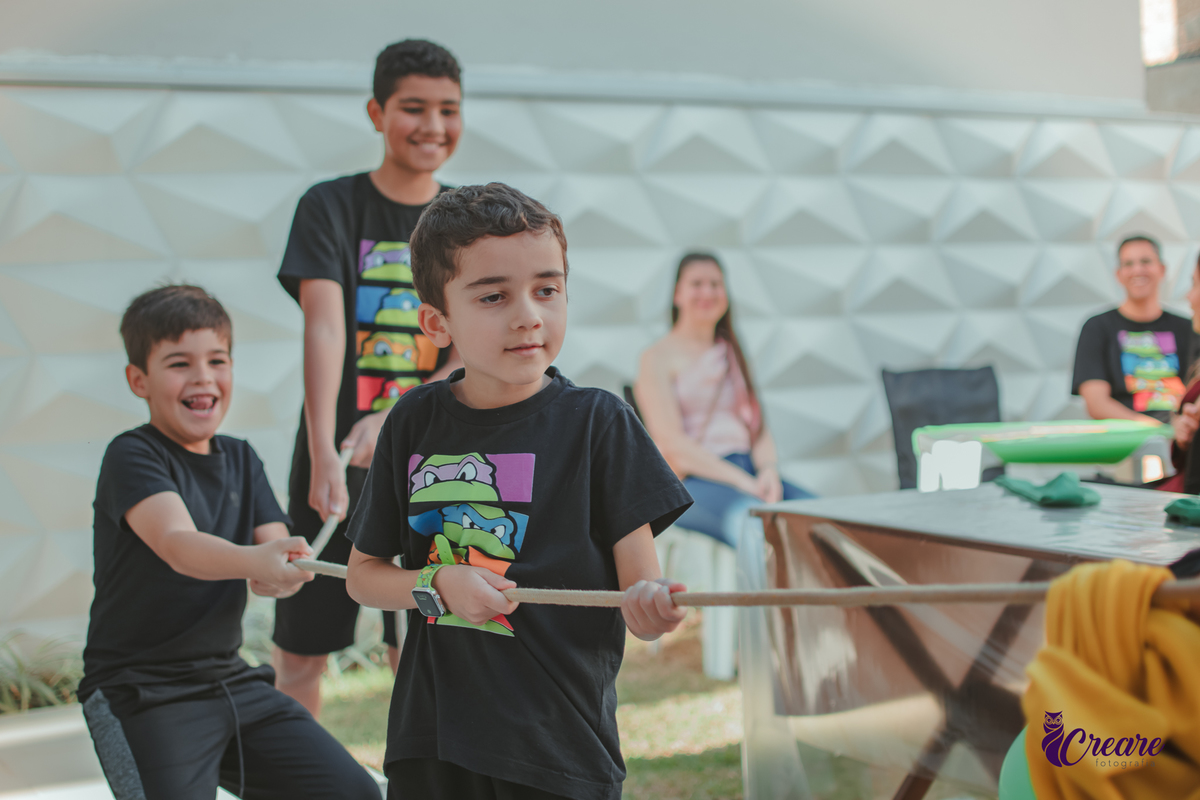 Crianças Brincando de cabo de guerra durante uma festa de aniversário em casa.