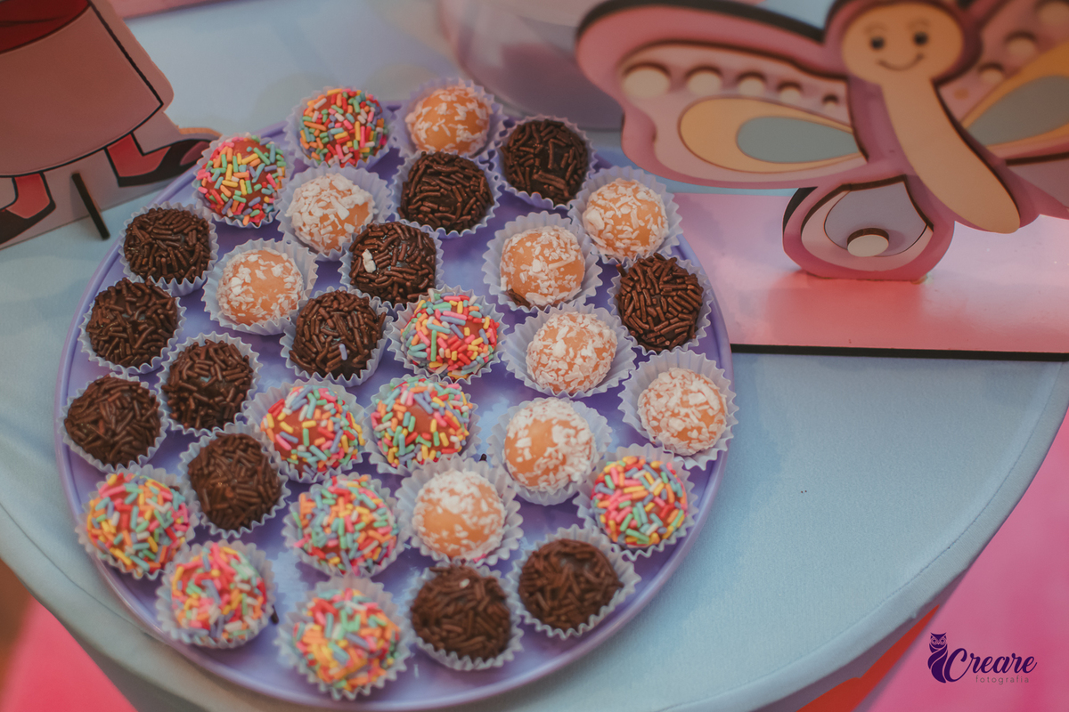 Docinhos de aniversário infantil com decoração de uma borboleta de madeira ao lado.