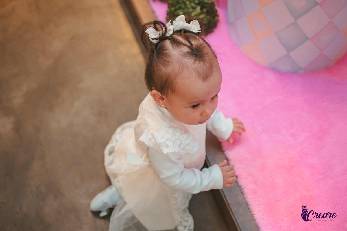 Uma bebê próxima a mesa de decoração do seu aniversário de 1 ano.