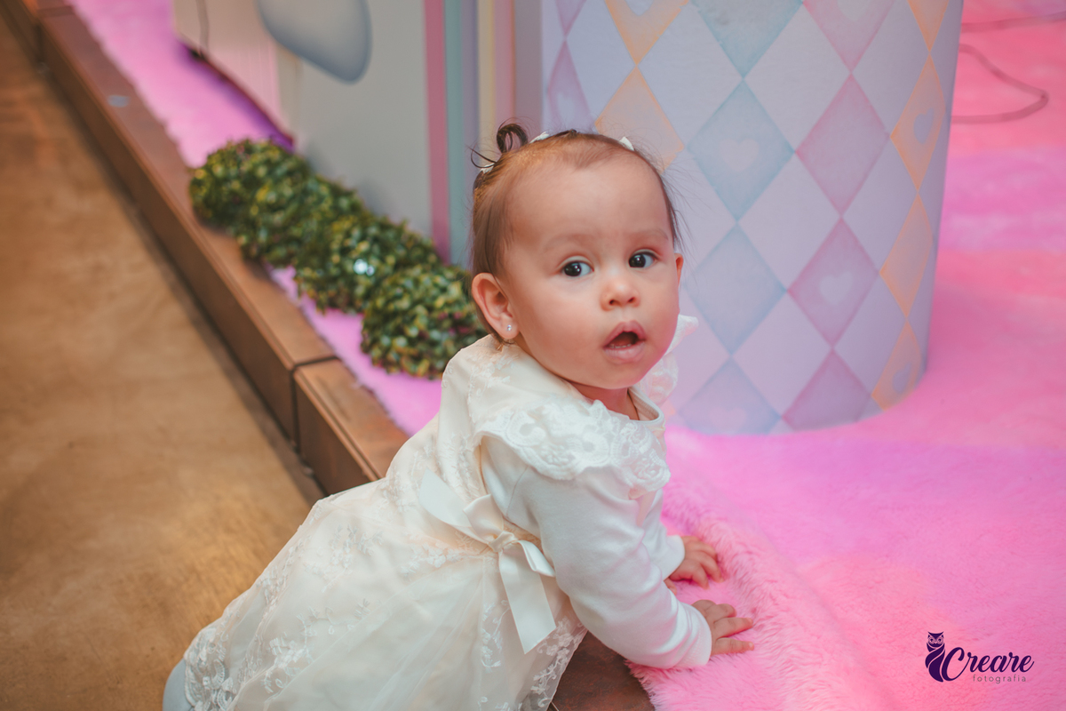 Uma bebê próxima a mesa de decoração do seu aniversário de 1 ano.