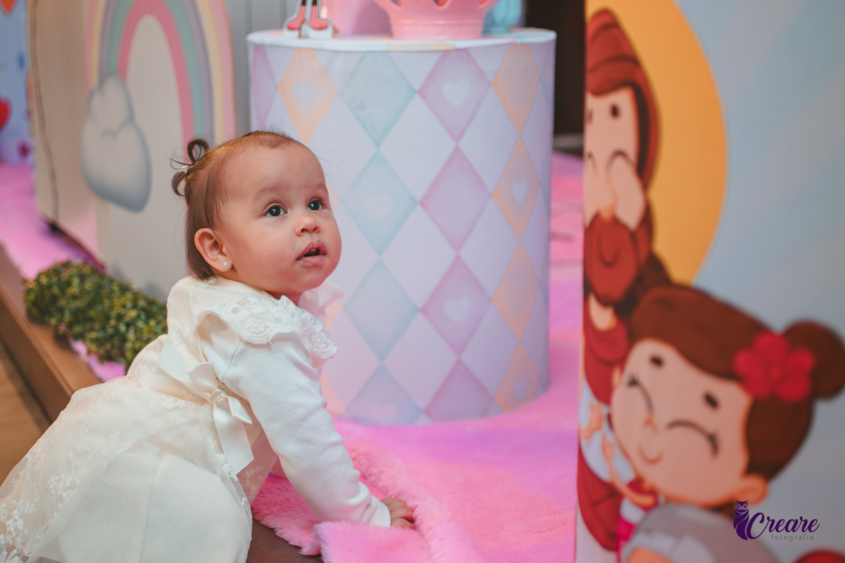Uma bebê próxima a mesa de decoração do seu aniversário de 1 ano.