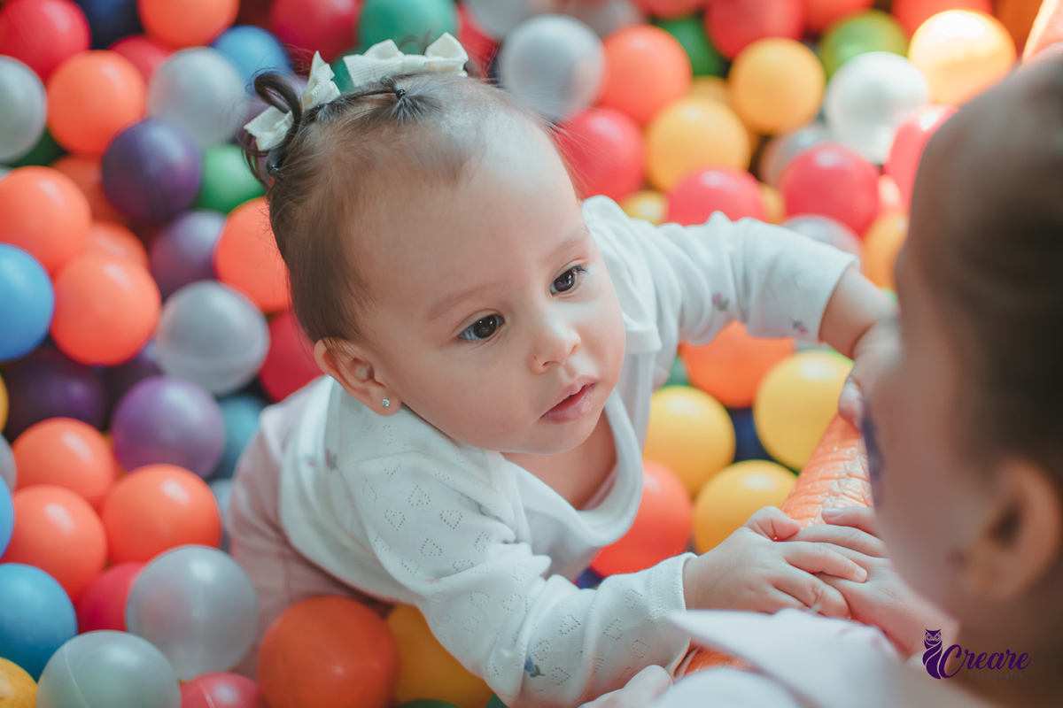 Uma bebê brincando nas piscina de bolinhas durante sua festa de aniversário de 1 ano.