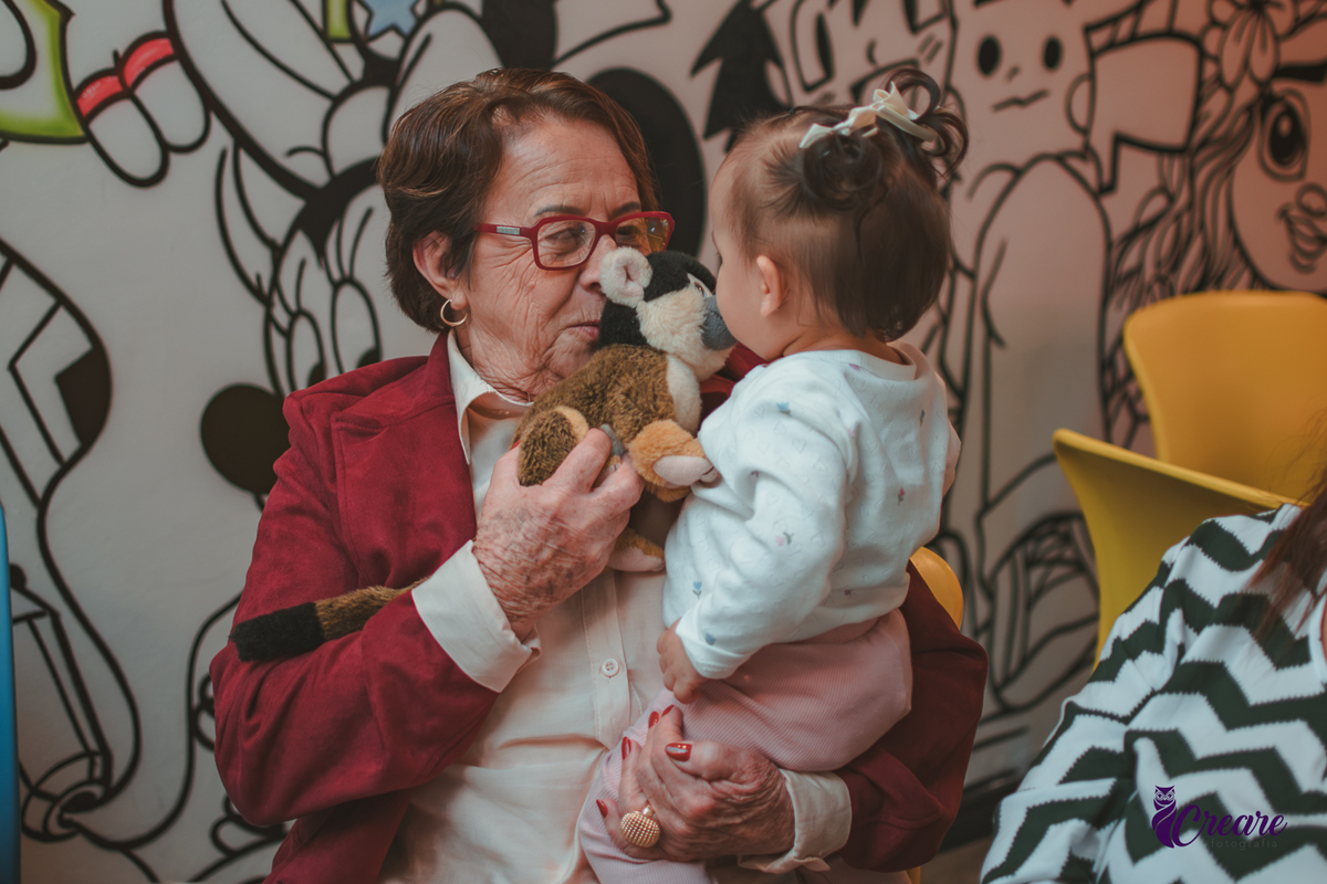 Uma bebê brincando com sua bisavó, durante sua festa de aniversário de 1 ano.