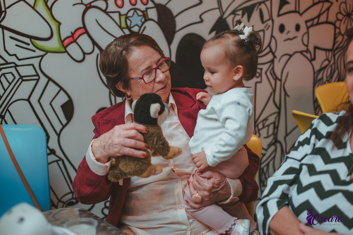 Uma bebê brincando com sua bisavó, durante sua festa de aniversário de 1 ano.
