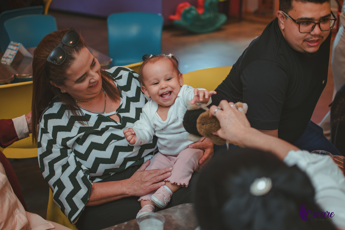 Uma bebê brincando com sua Tia, durante sua festa de aniversário de 1 ano.