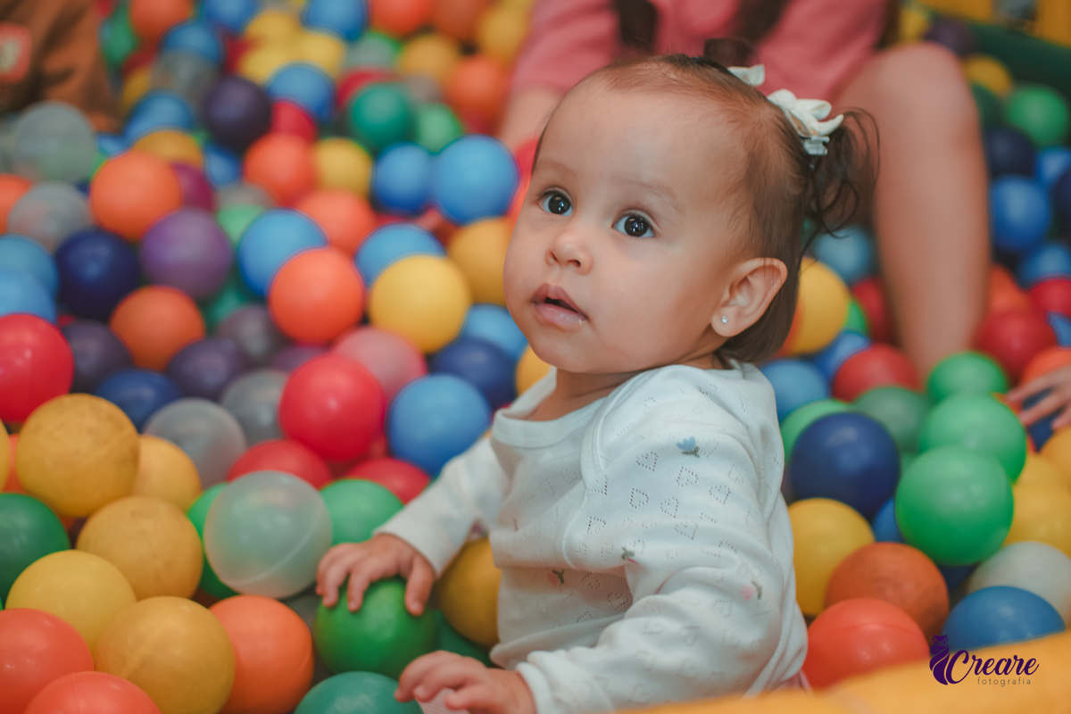 Uma bebê brincando nas piscina de bolinhas durante sua festa de aniversário de 1 ano.